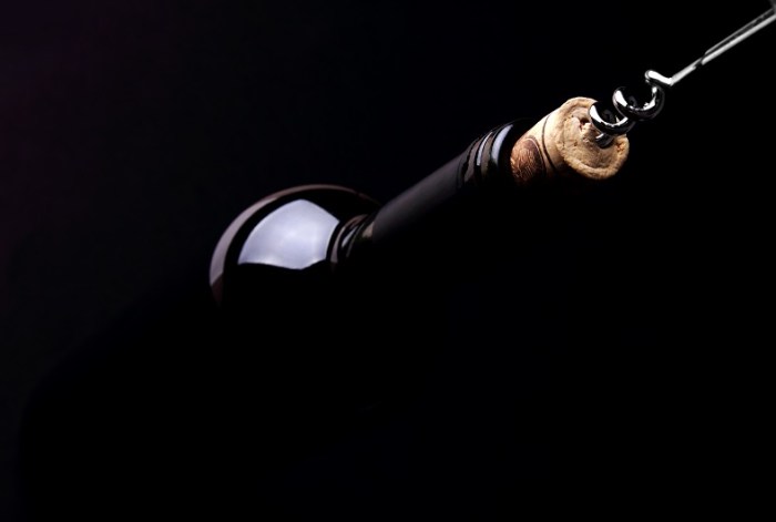 Opening a bottle of wine, on dark background